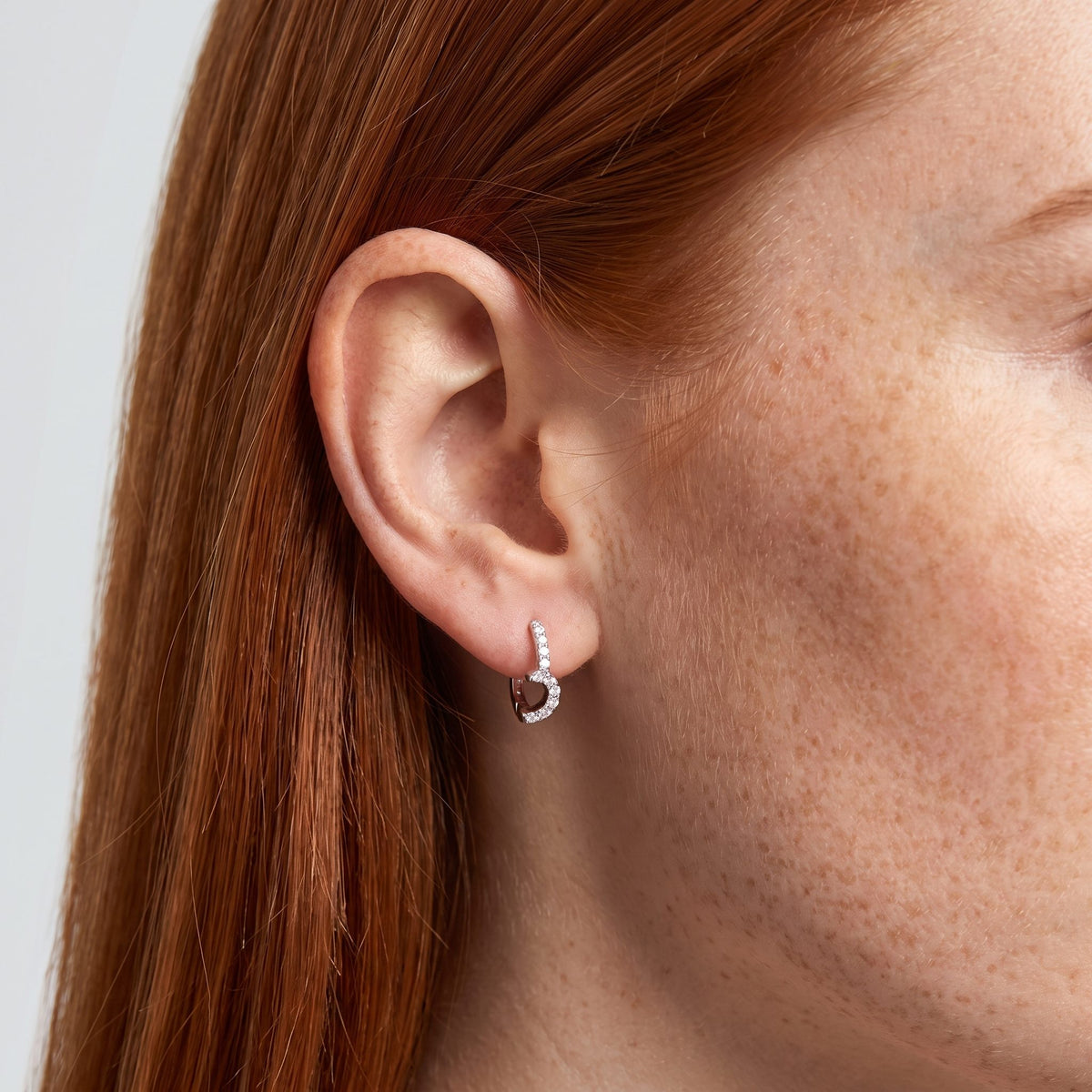 Woman wearing the Anais Crystal Moon Hoops on the lobe featuring a silver crescent shape