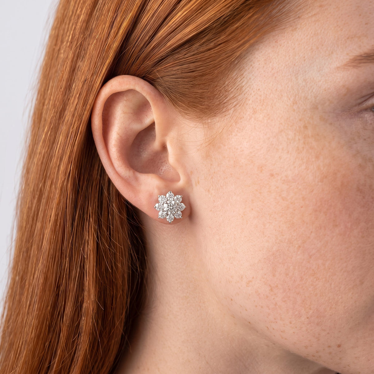 Woman wearing the Andora Silver Crystal Earrings flat to the lobe in a sparkling flower shape