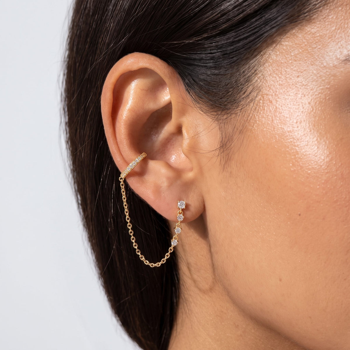 Woman wearing the Andra Chain Cuff Earrings on her ear with a gold chain draping below the lobe