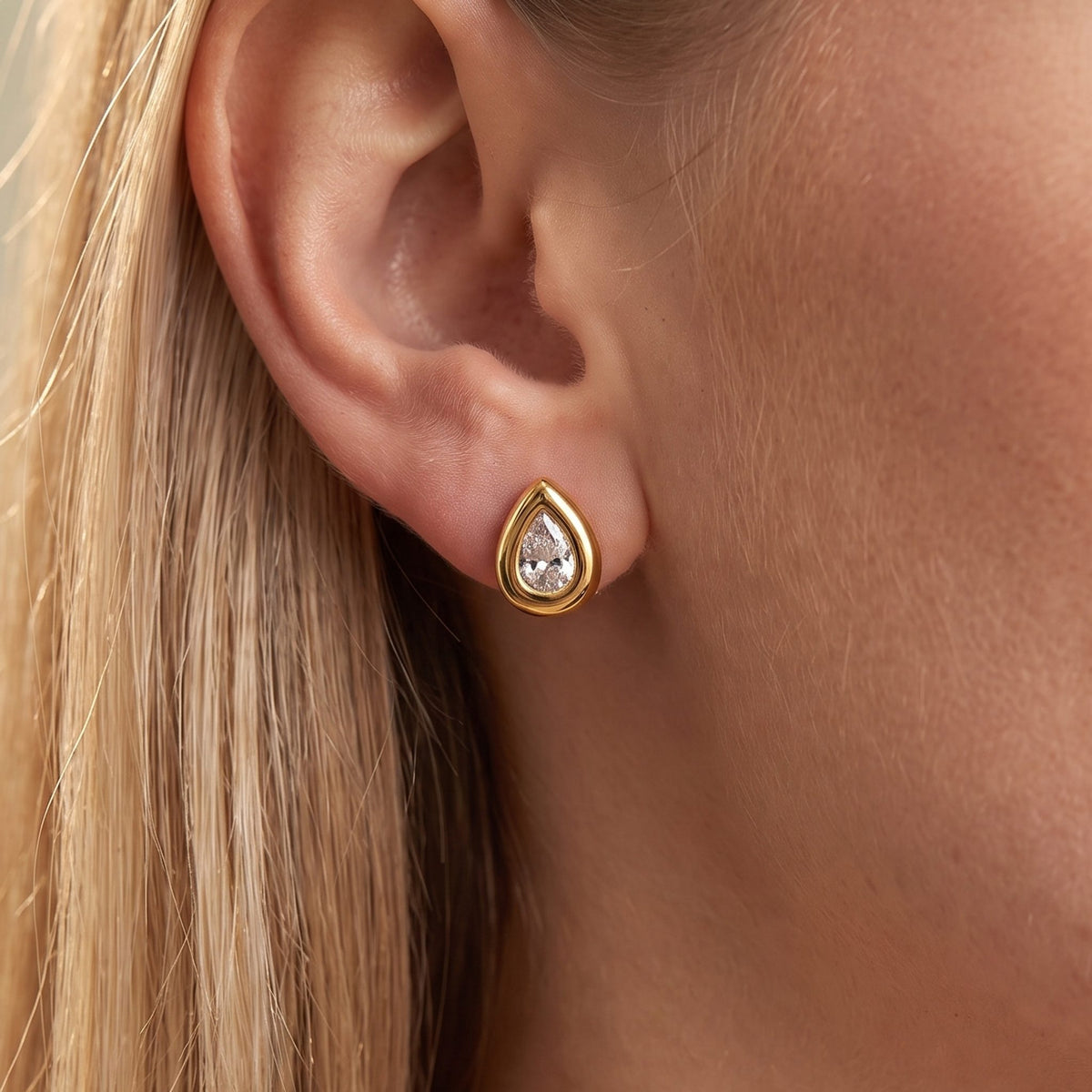 Close-up of the Bold Teardrop Studs on the ear showcasing a teardrop crystal in a thick gold bezel
