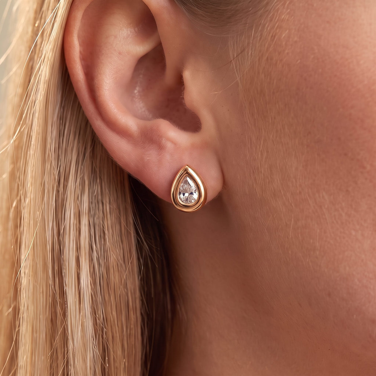 Close-up of the Bold Teardrop Studs on the ear showcasing a teardrop crystal in a thick rose gold bezel