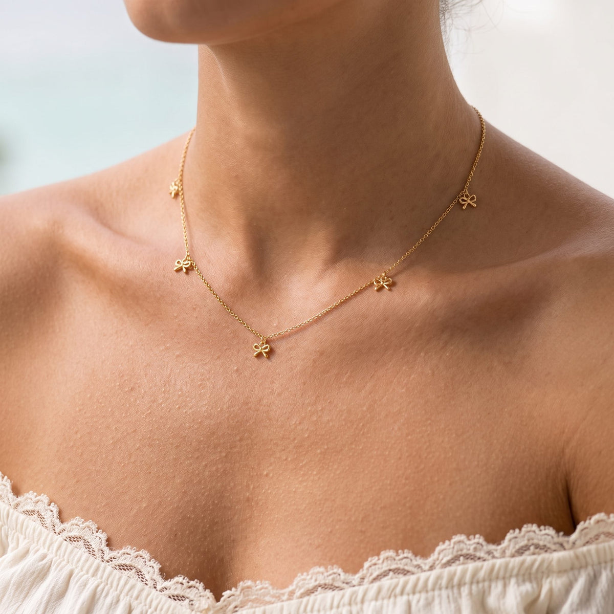 Wider view of a woman wearing the Bow Drop Necklace