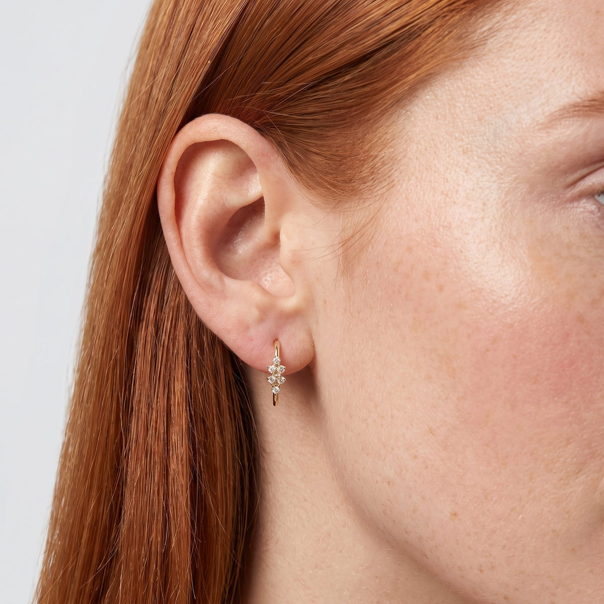 Woman wearing the Camila Crystal Cluster Earrings through the lobe with a gold cluster hanging below