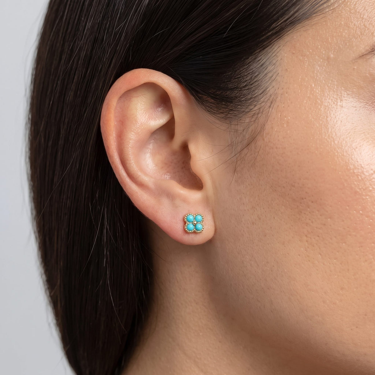 Woman wearing the Cassidy Turquoise Stud Earrings on the lobe, featuring four round turquoise stones in gold