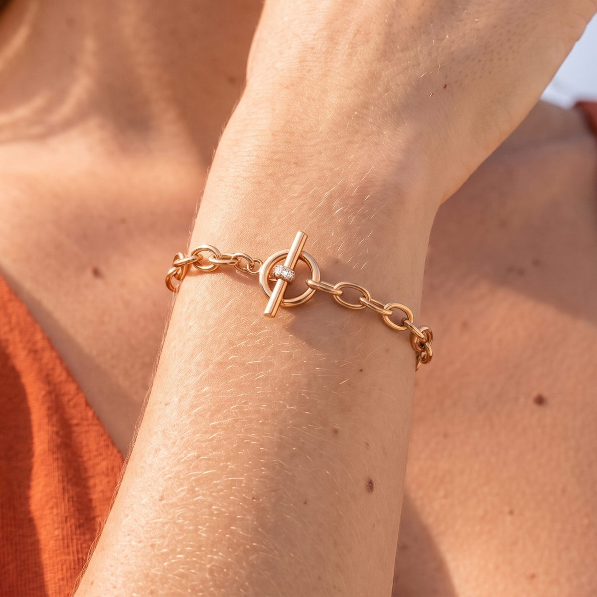 Close-up of the Circle Toggle Bracelet on the wrist, highlighting the small crystal-accented bar closure in sunlight, in rose gold