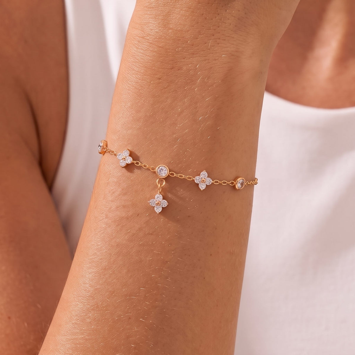 Close-up of the Clover Dangle Bracelet on her wrist highlighting its crystal floral charms, in rose gold