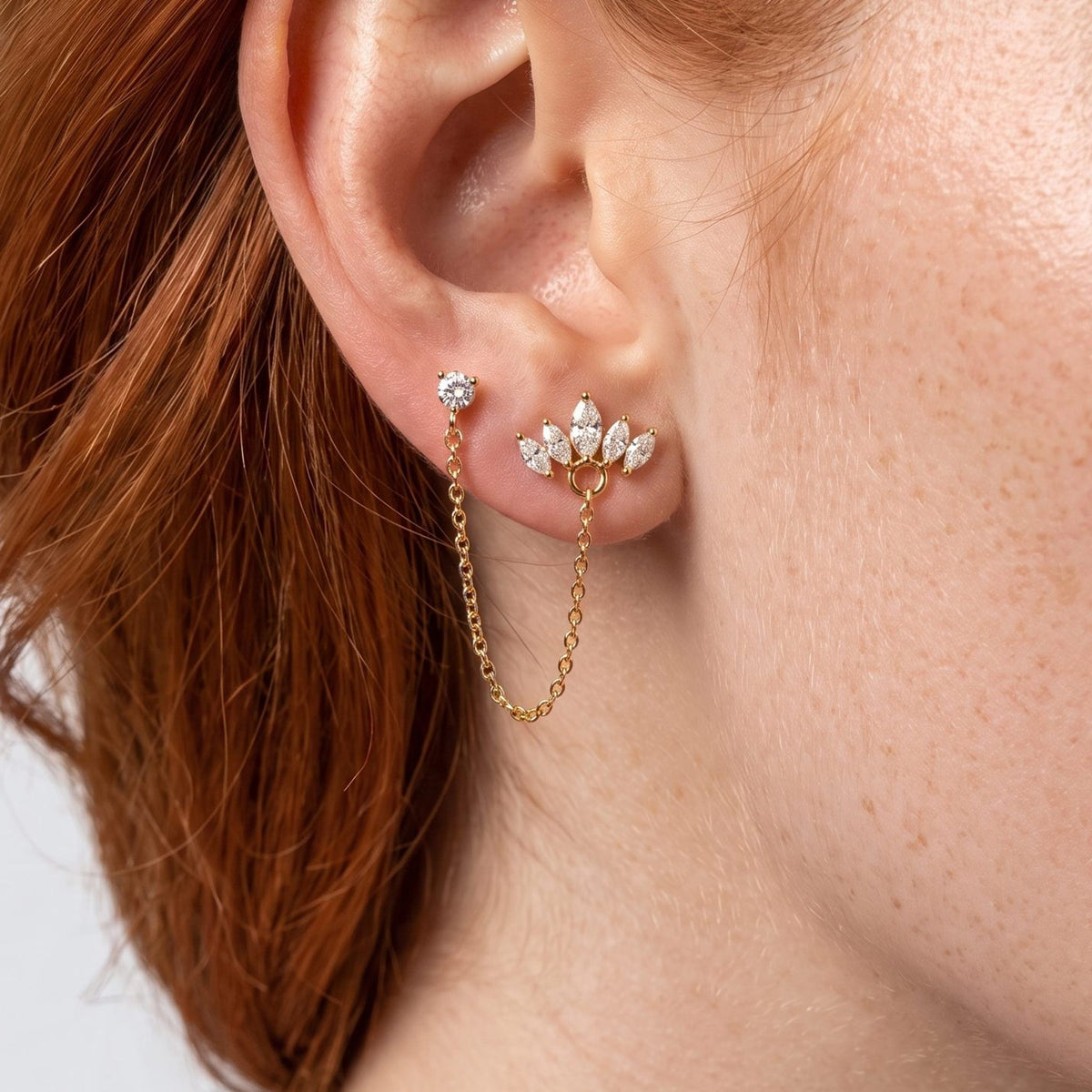 Woman wearing the Colette Crown Crystals Gold Earring on the lobe with a gold chain hanging below
