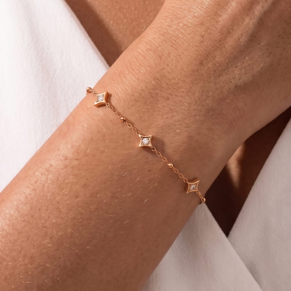 Close-up of the Constellation Bracelet on the wrist featuring star-shaped crystal charms, in rose gold