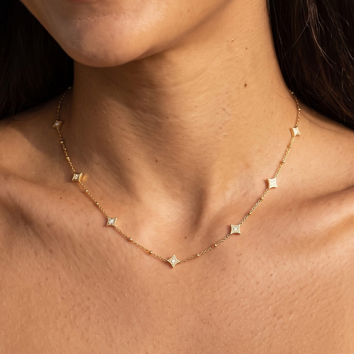 Close-up of the Constellation Necklace at the collarbone, featuring delicate star pendants with crystals