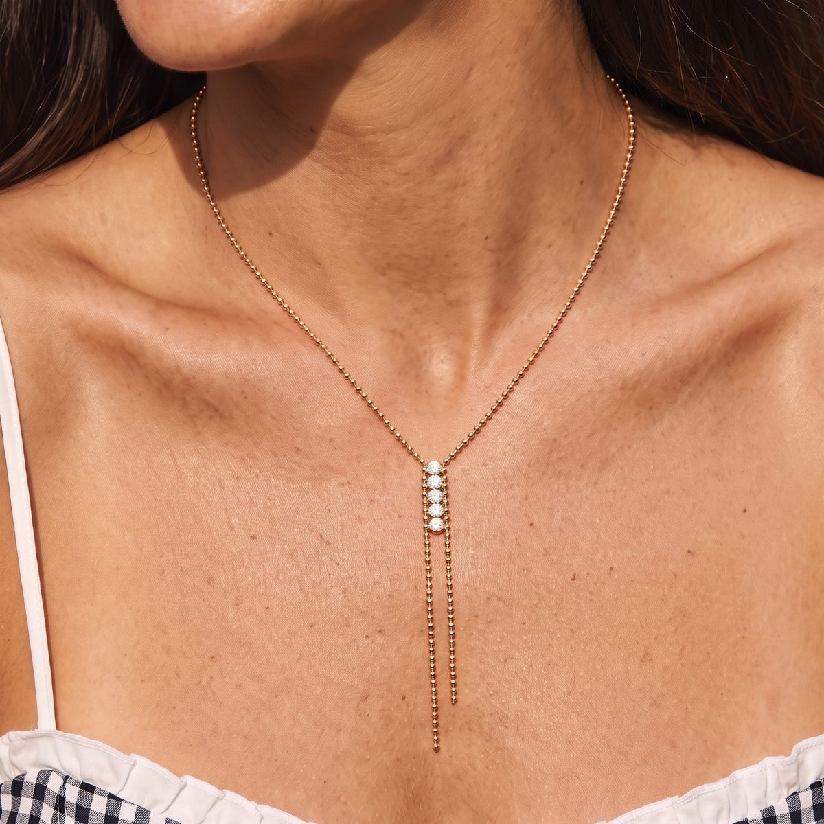 Close-up of the Crystal Bar Lariat Necklace at the collarbone, featuring four sparkling crystals on a rose gold bead chain