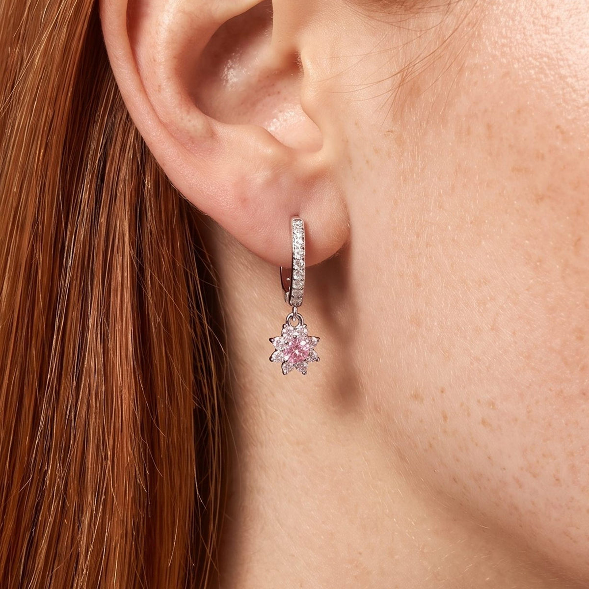 Woman wearing the Élodie Rosé Crystal Hoops hanging below the lobe with a pink flower charm