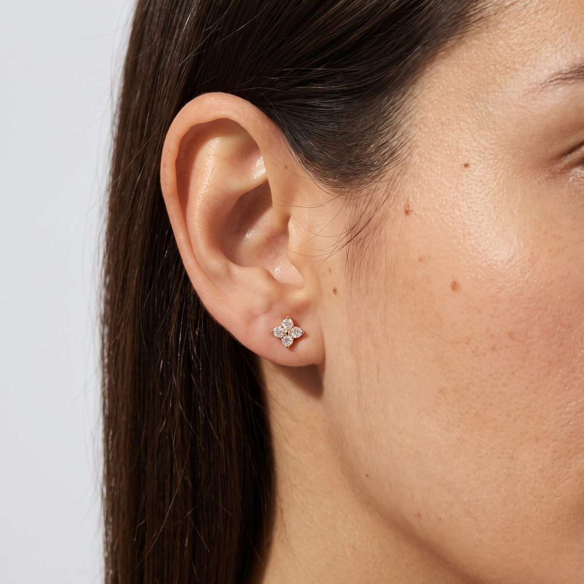 Woman wearing the Emma Crystal Clover Studs on the lobe, showing the gold four-petal crystal design