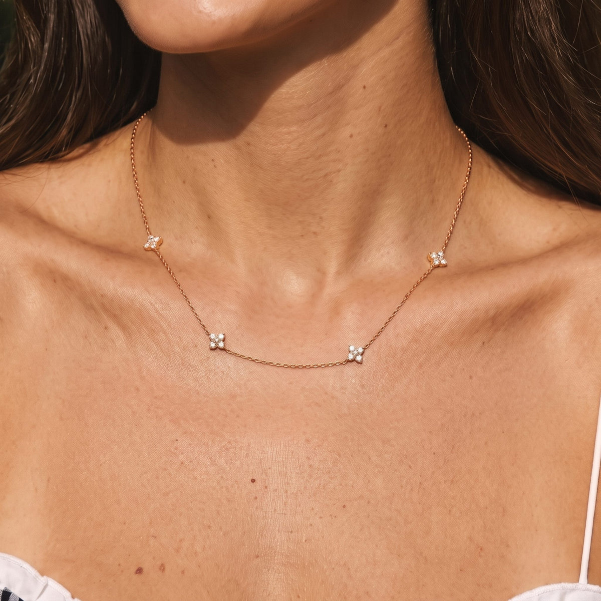 Close-up of the Four Bloom Necklace worn on the neckline, in rose gold