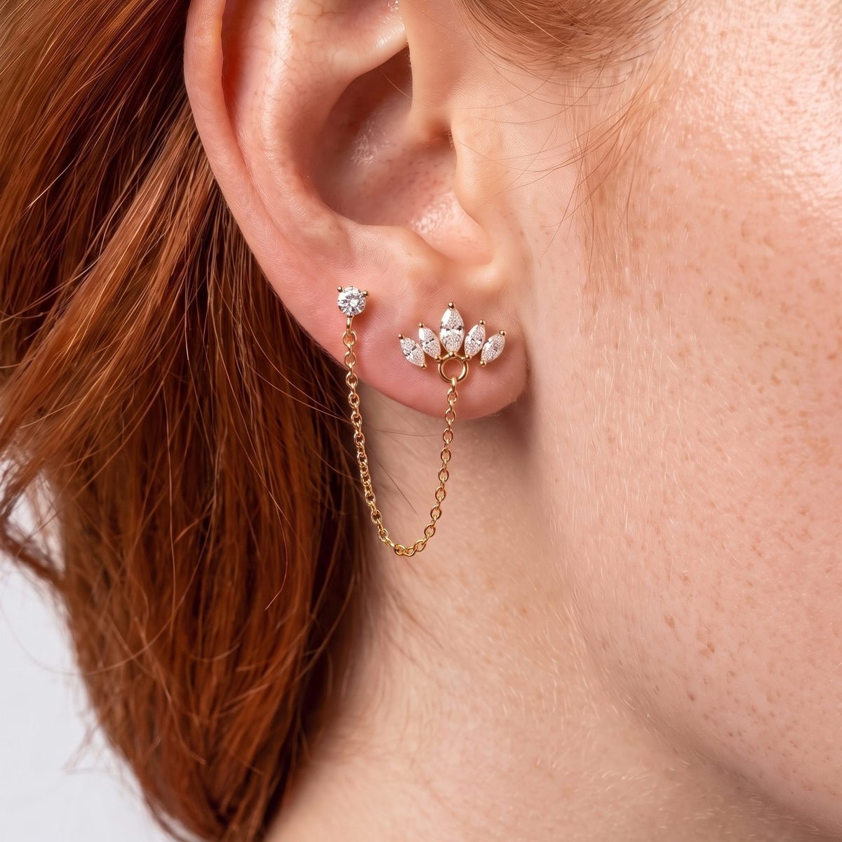 Woman wearing the Crown Earring in rose gold on the lobe with a chain hanging below