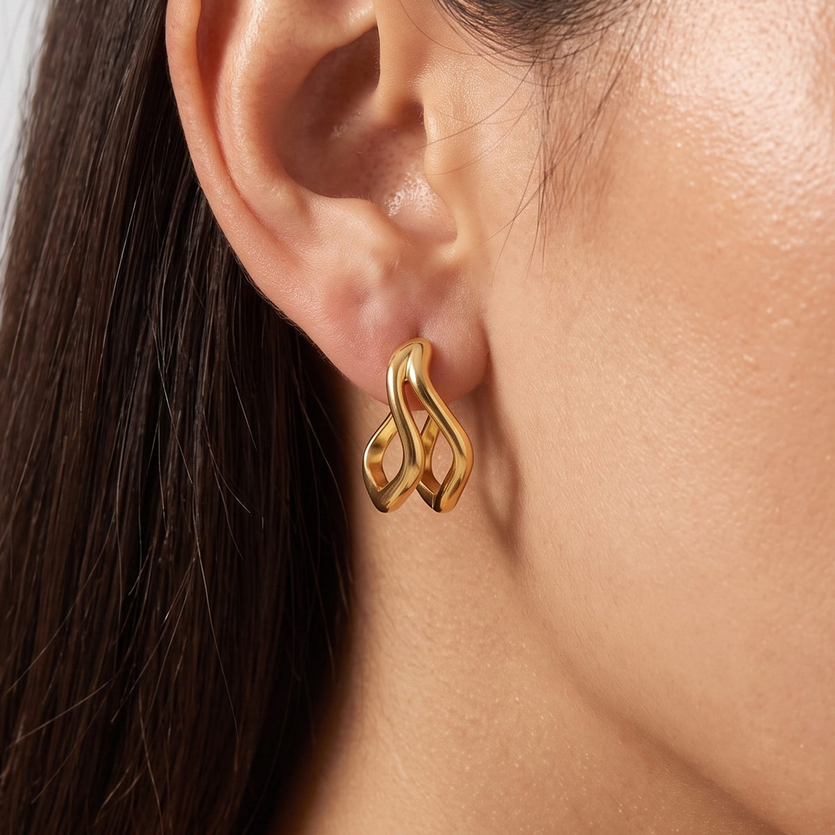 Close-up of the Gold Double Wave Hoops on the ear highlighting their polished curved design