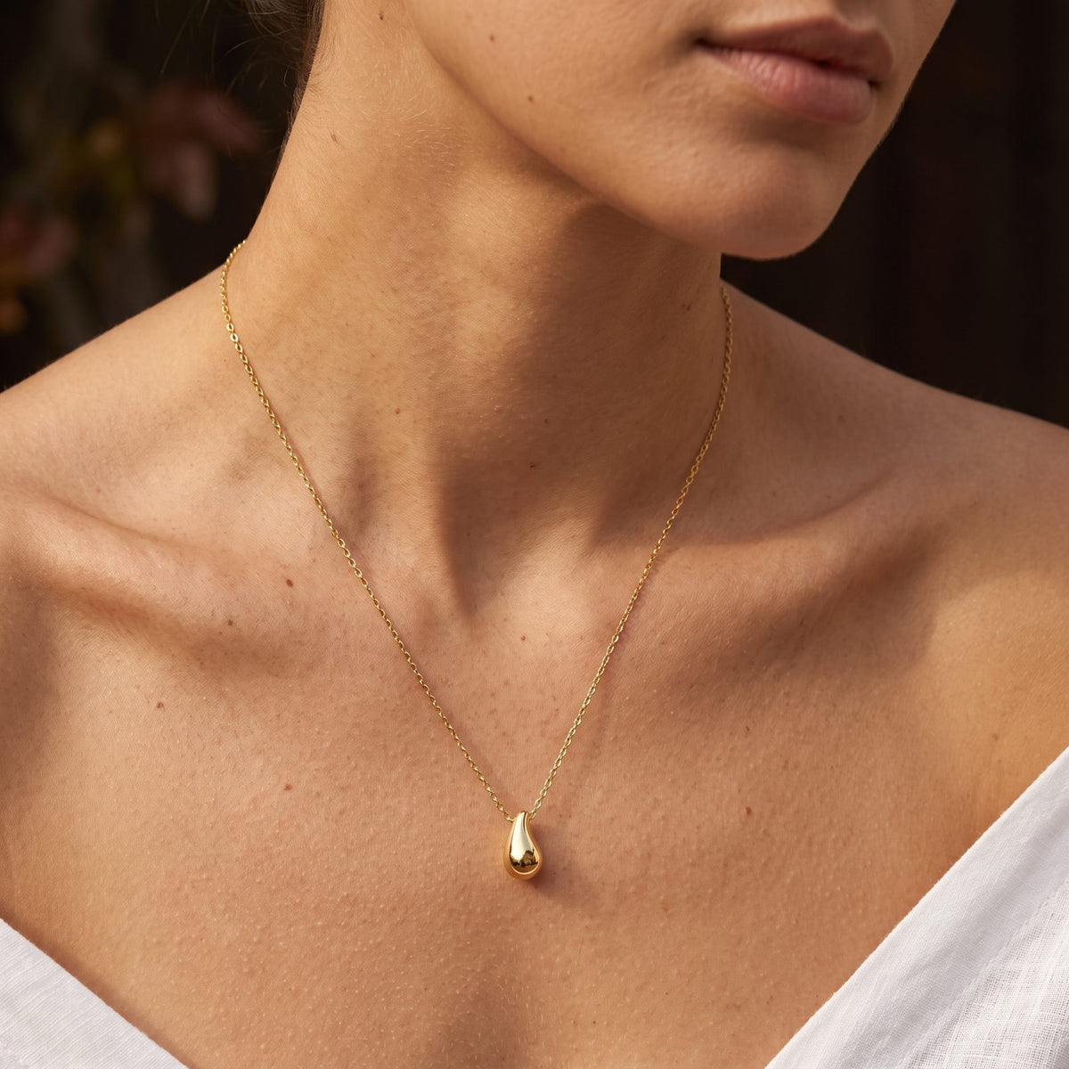 Wider view of a woman wearing the Gold Drop Pendant