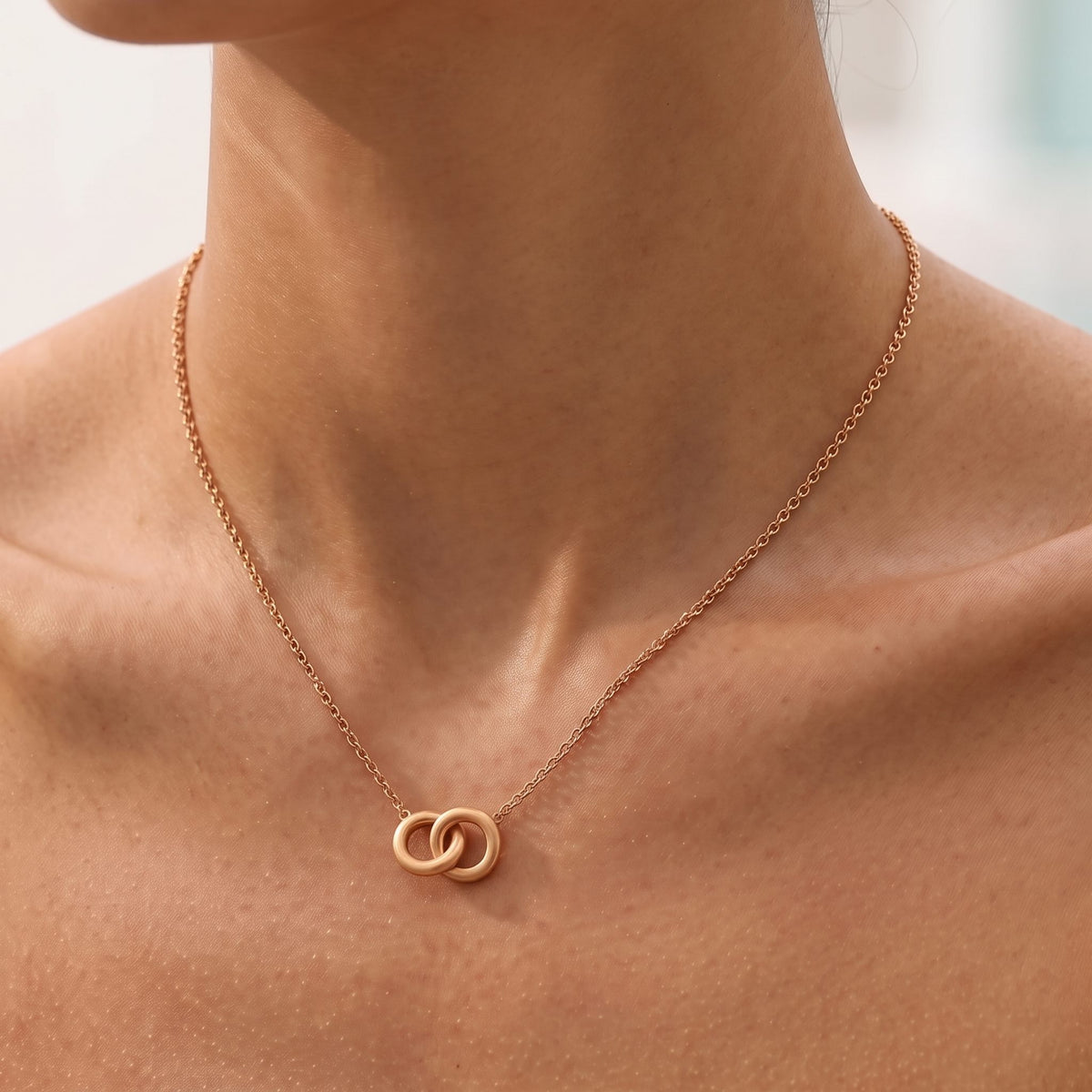 Close-up of the rose gold Interlock Necklace at the collarbone showing two interlocking rings