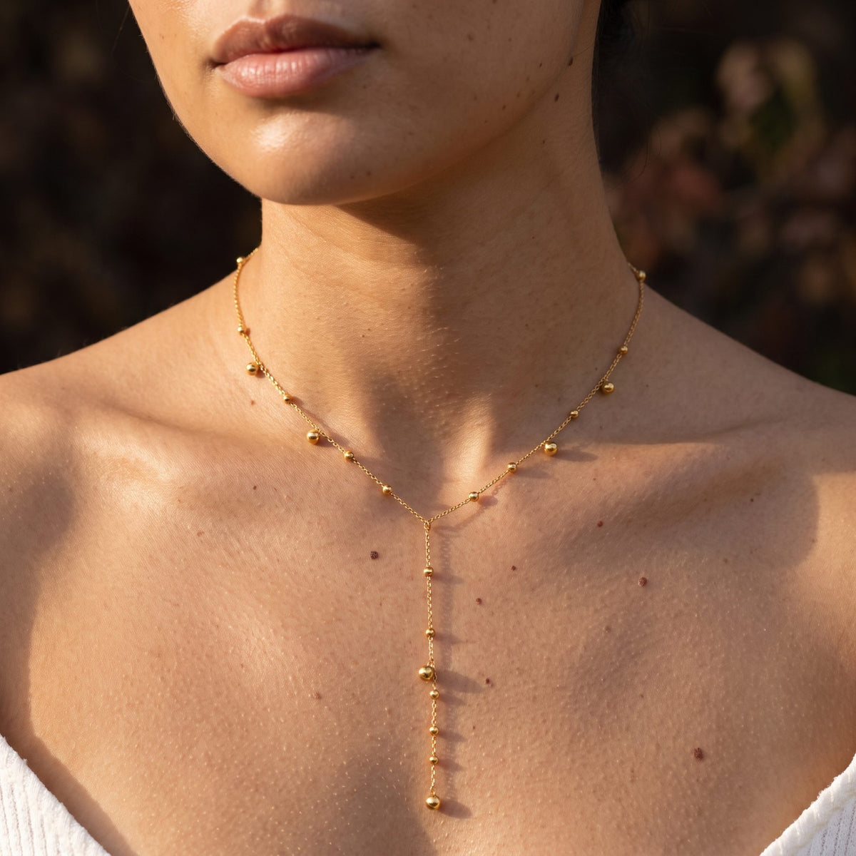 Woman wearing the Golden Lariat Necklace on the neckline