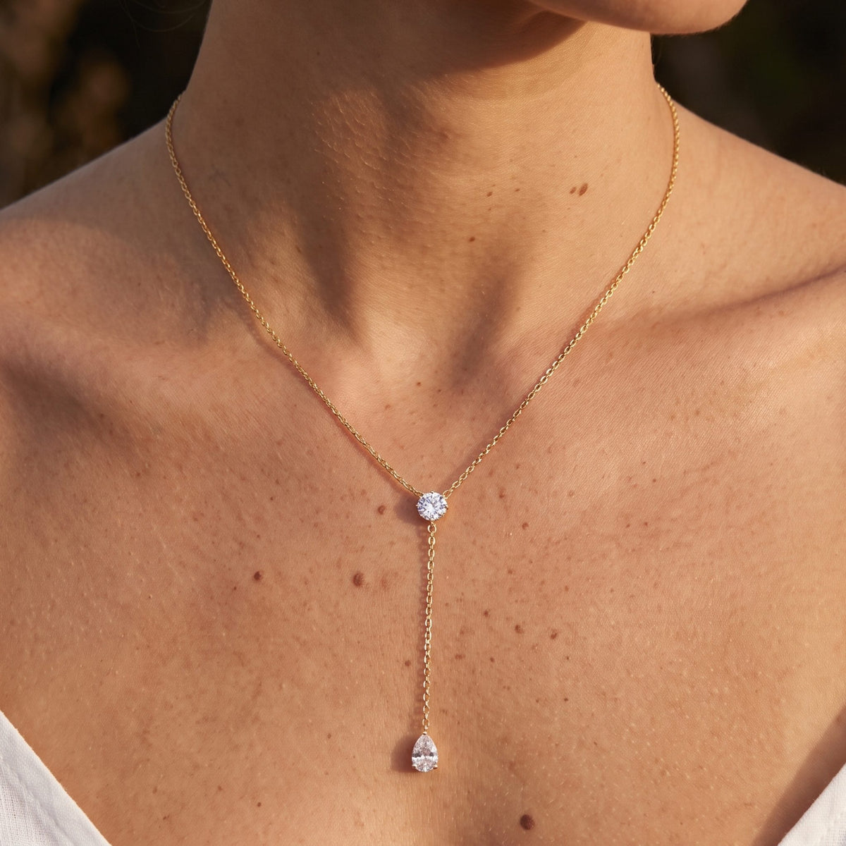 Close-up of the Halo Lariat Necklace at the throat, highlighting sparkling crystals on a delicate gold chain
