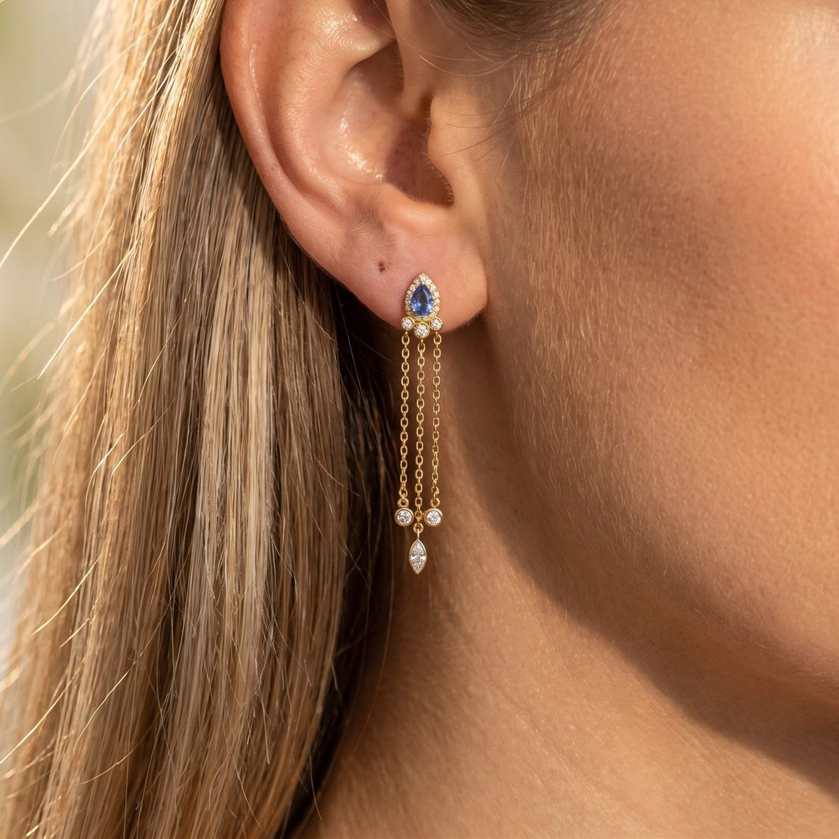 Woman wearing the Isabella Radiant Drop Earrings hanging below the lobe with three delicate gold chains
