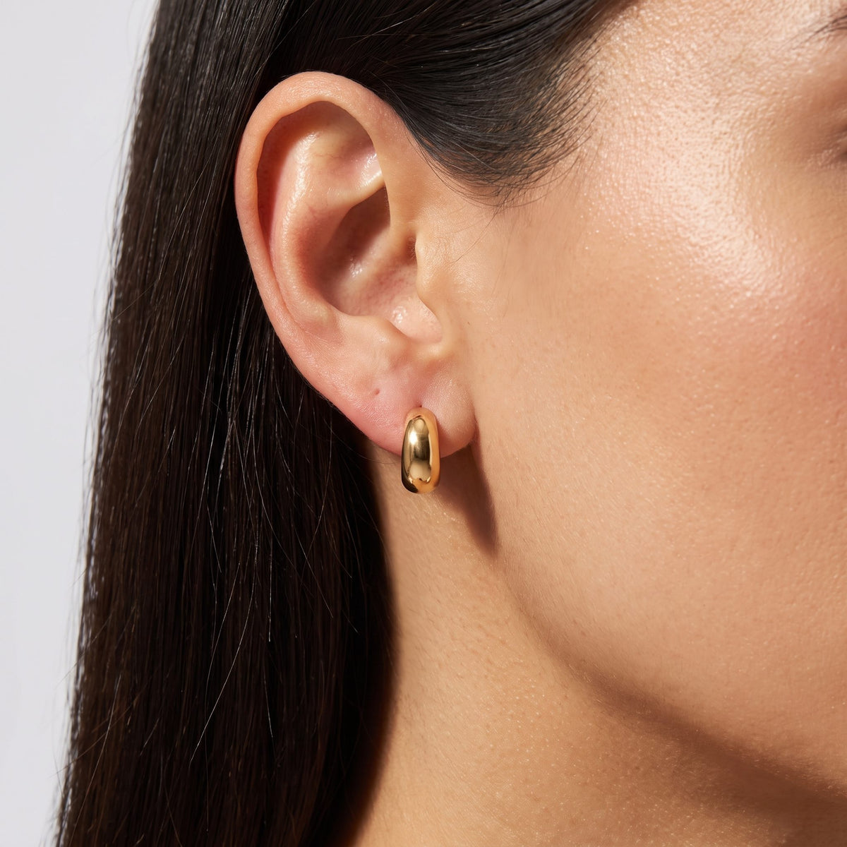Woman wearing the Juliet Gold Stud Earrings on the lobe as a thick, polished gold hoop