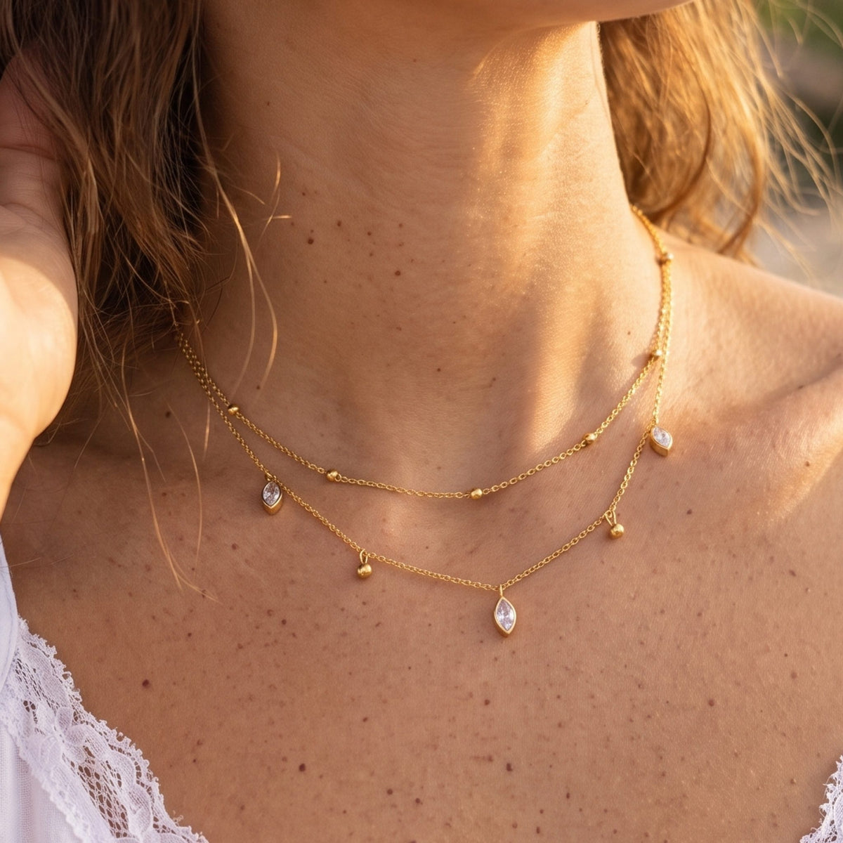 Close-up of the Layered Marquise Necklace worn at the collarbone, highlighting its dangling crystals in golden light