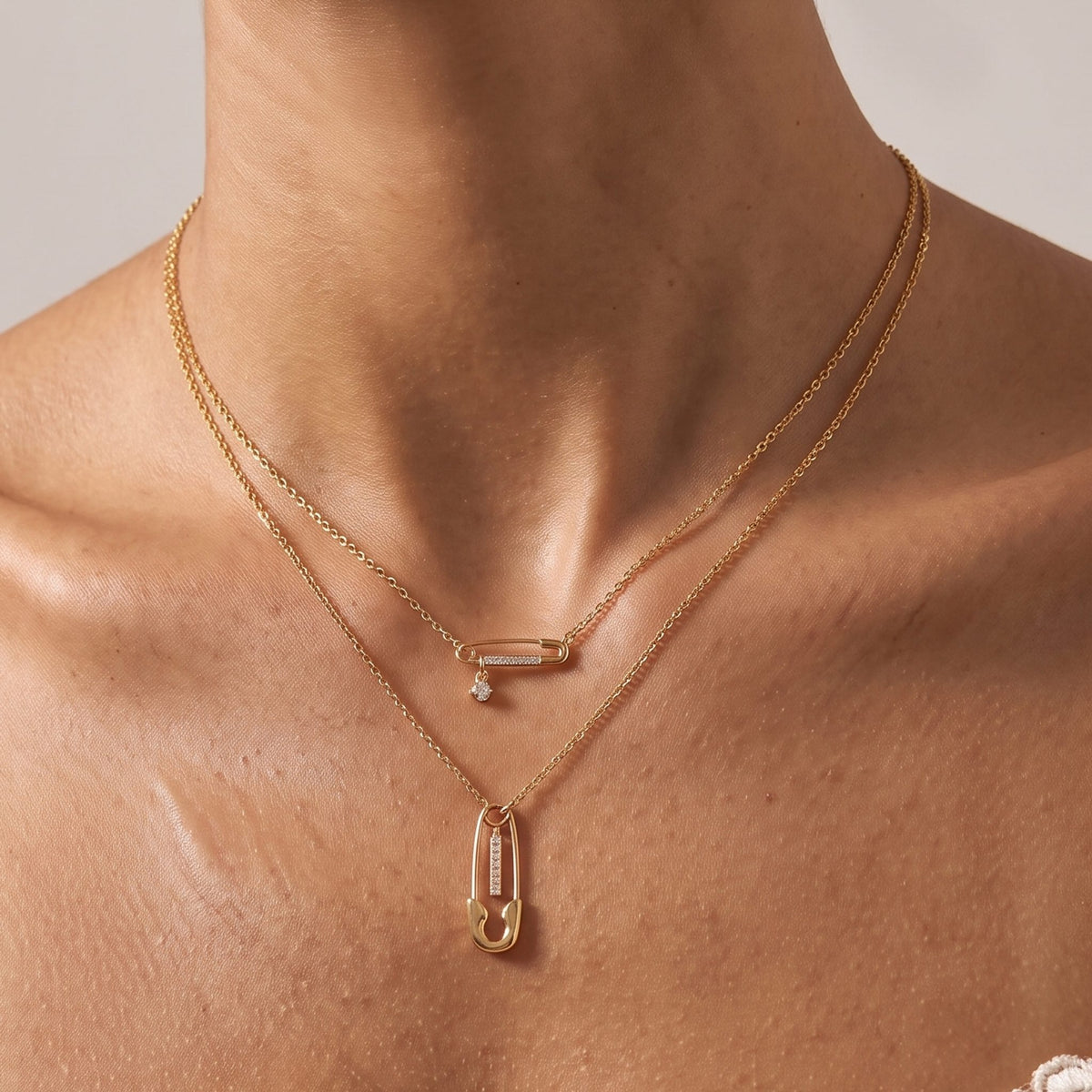 Close-up of the Layered Safety Pin Necklace at the collarbone showing the crystal-embellished charms