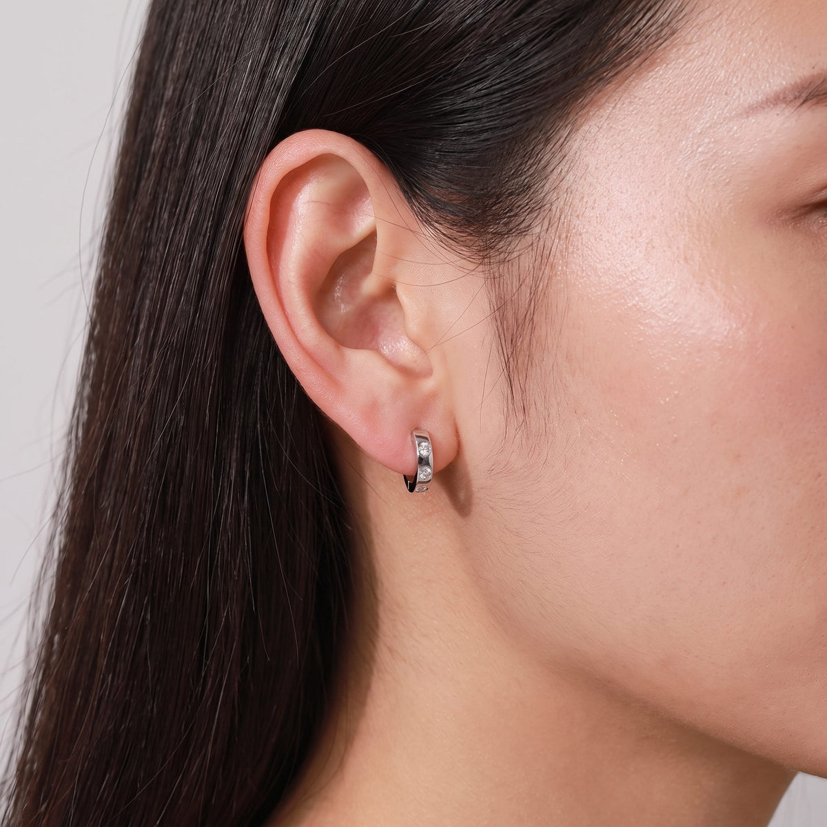 Woman wearing the Lilou Minimalist Silver Hoops on the lobe with three small inset crystals