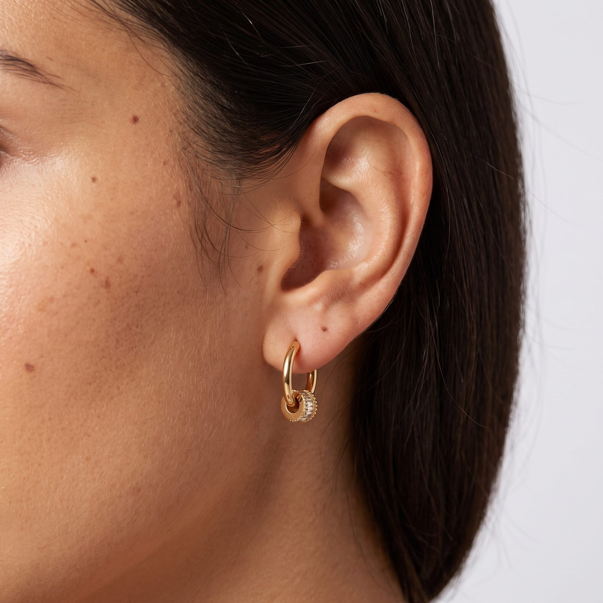 Woman wearing the Maia Crystal Earrings through the lobe with a small crystal-lined gold charm