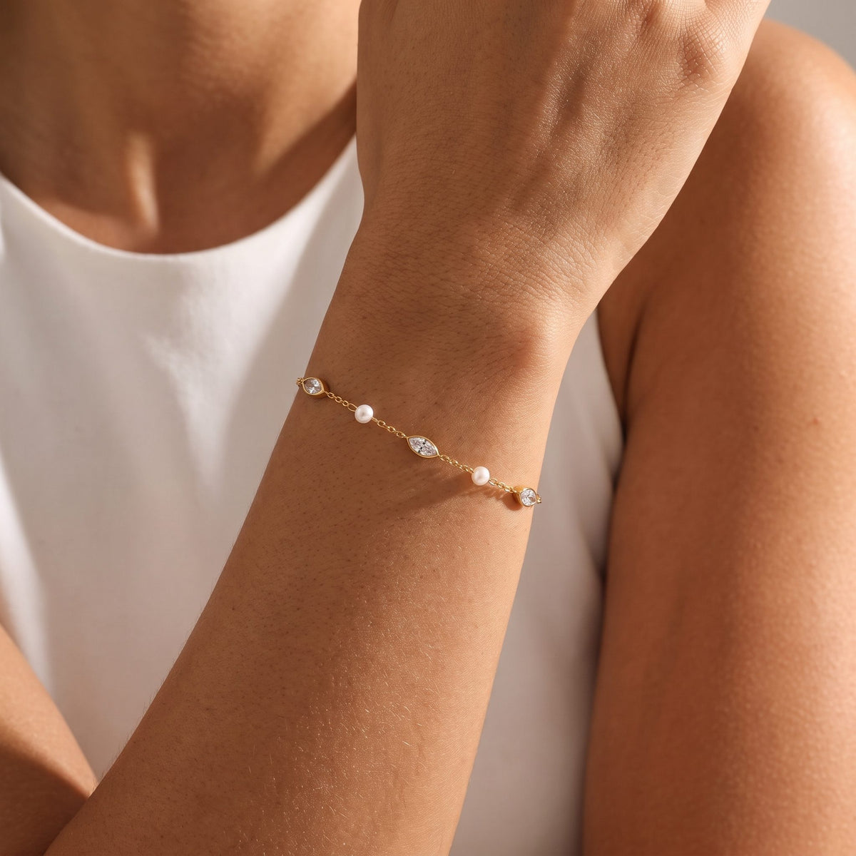 Woman wearing the Marquise & Pearl Bracelet on the wrist, her hand resting near her shoulder