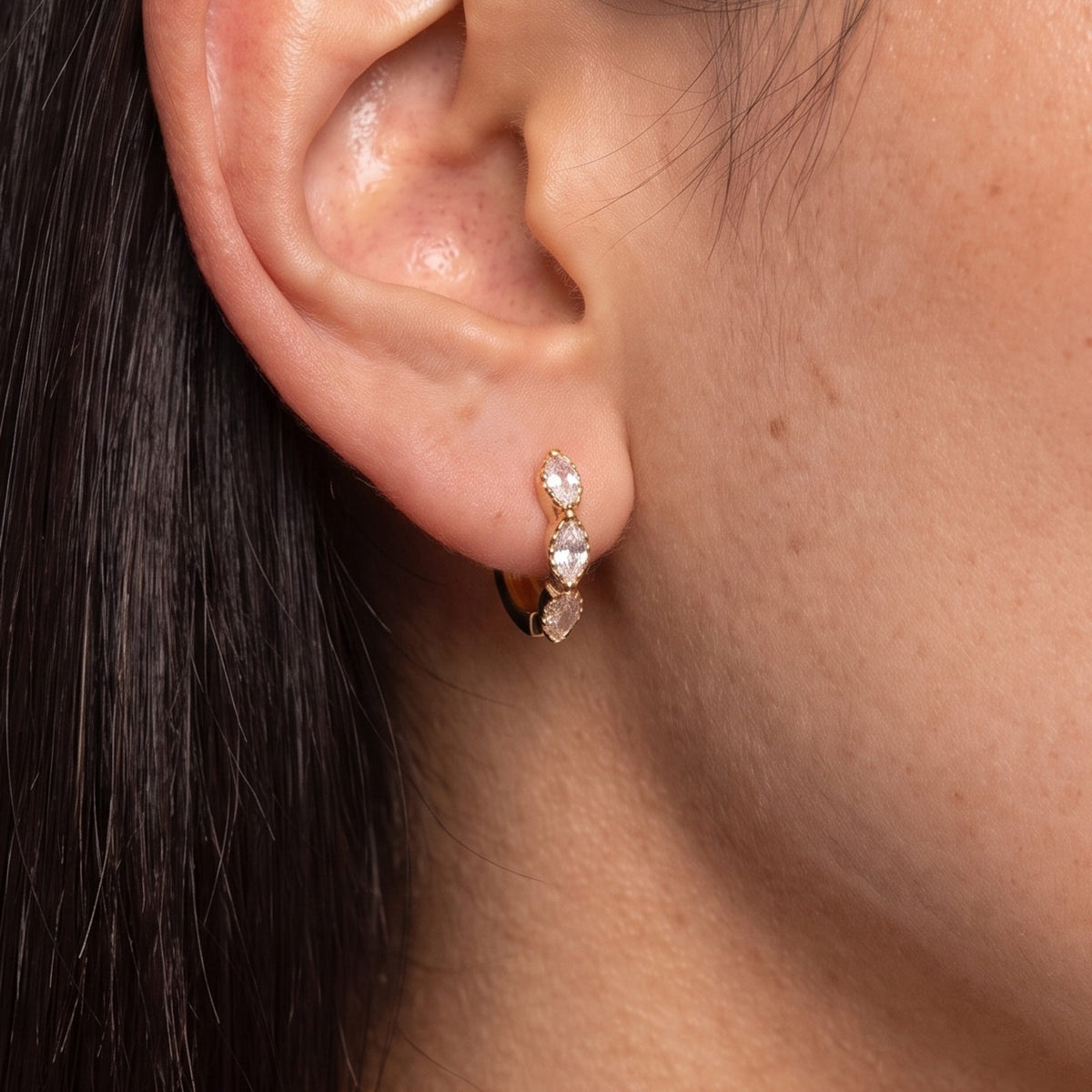 Close-up of the Marquise Trio Huggies on the ear, showing three marquise-cut crystals in gold