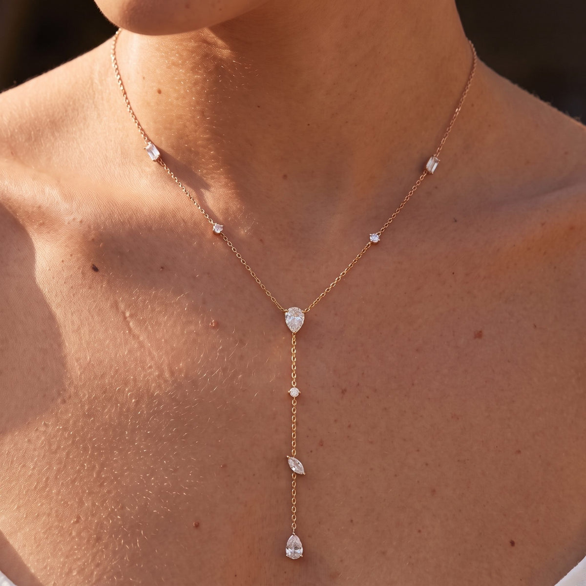 Close-up of the Mixed Cut Lariat Necklace worn at the collarbone showing sparking crystal charms, in rose gold