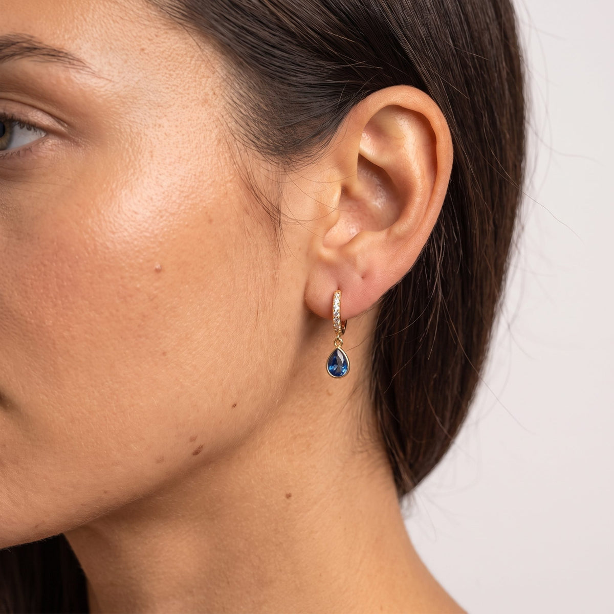 Woman wearing the Navy Teardrop Huggies on the ear, looking away from the camera