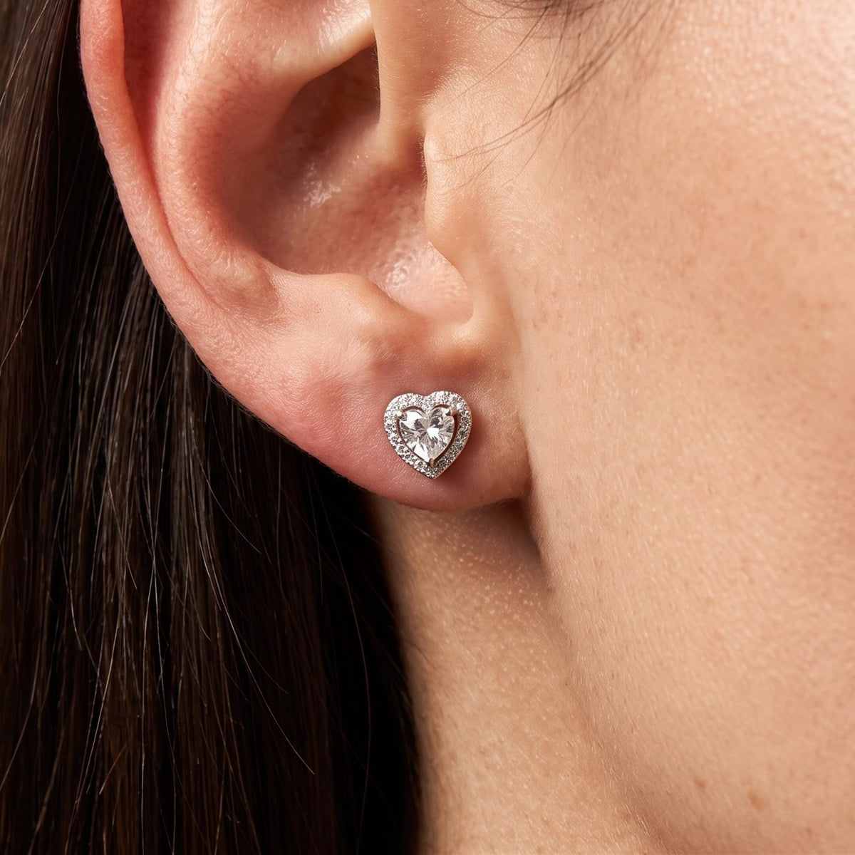 Woman wearing the Olivia Amour Halo Earrings flat to the lobe, featuring a silver-colored heart-shaped crystal