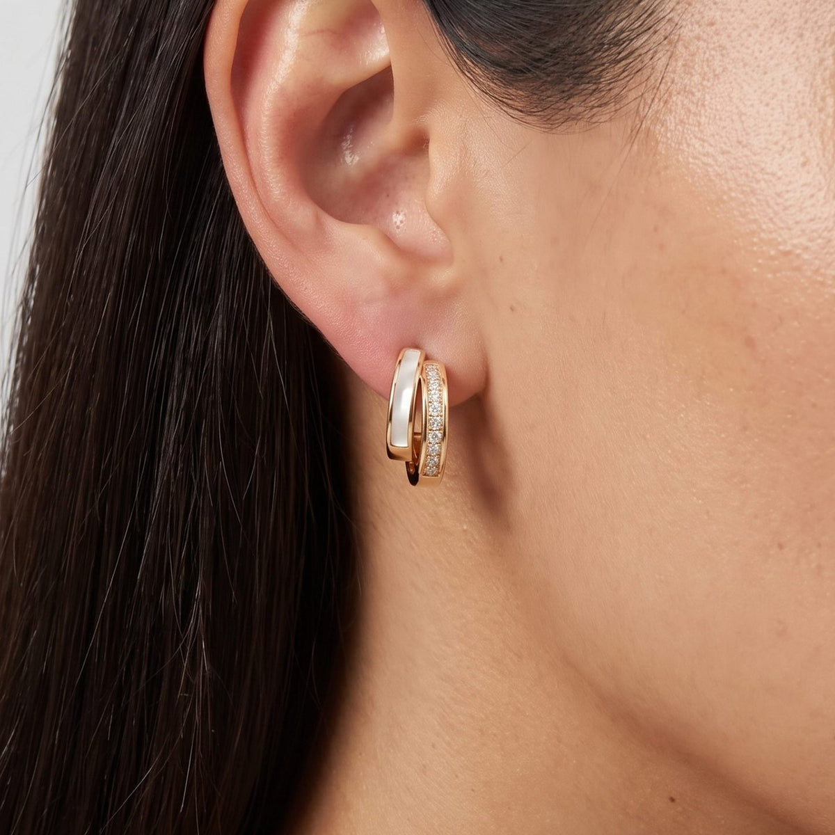 Woman wearing the Olivia Pearl & Crystal Earrings on her lobe, featuring a double gold hoop design