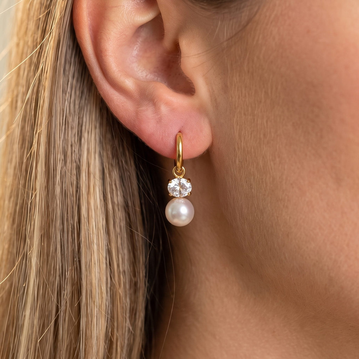Close-up of the Pearl Dangle Huggies on the ear featuring a crystal and pearl drop