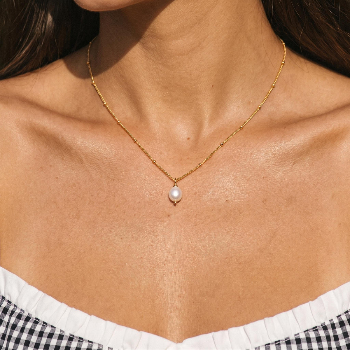 Close-up of the Pearl Drop Necklace worn on the neckline