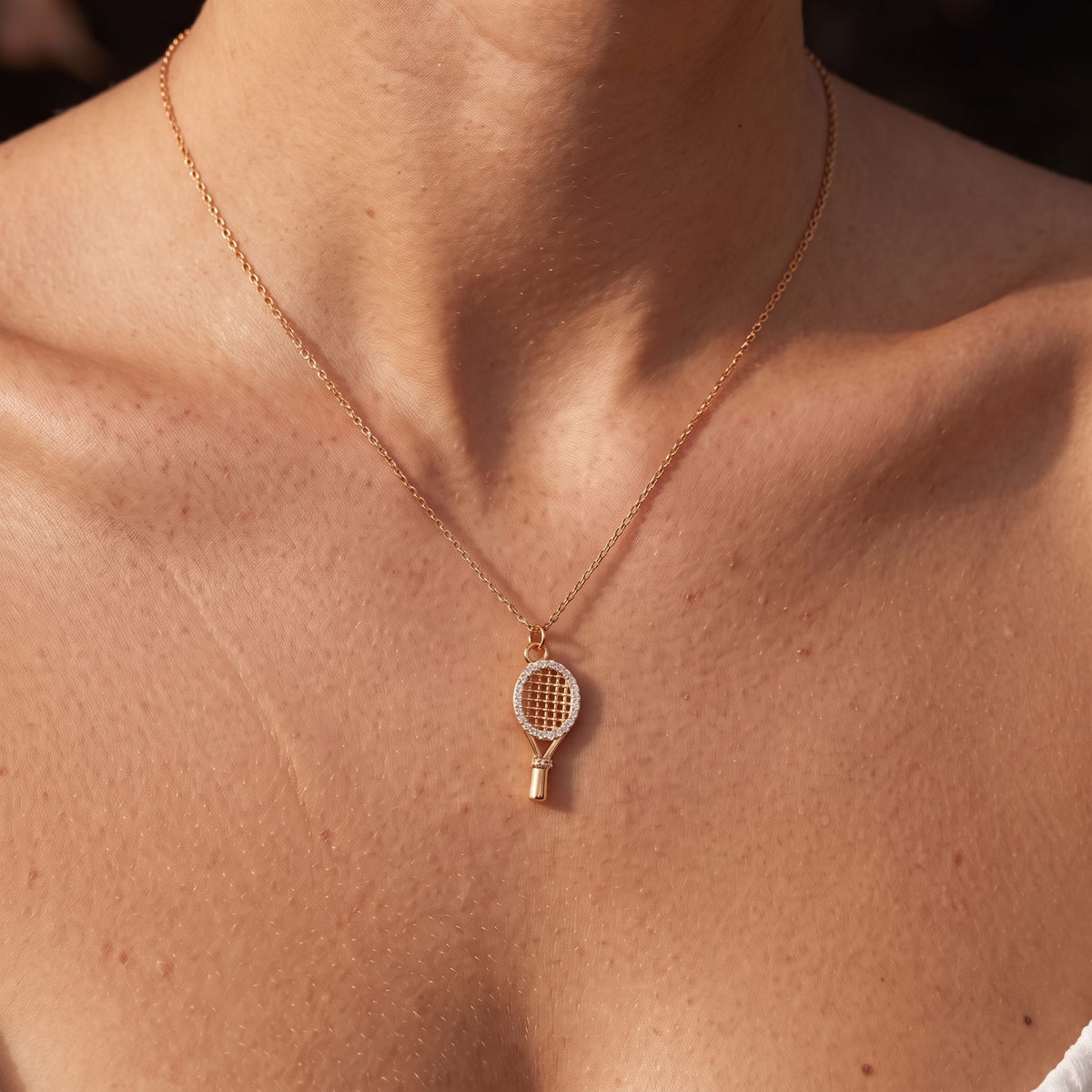 Close-up of the Racket Pendant worn on the neckline, in rose gold