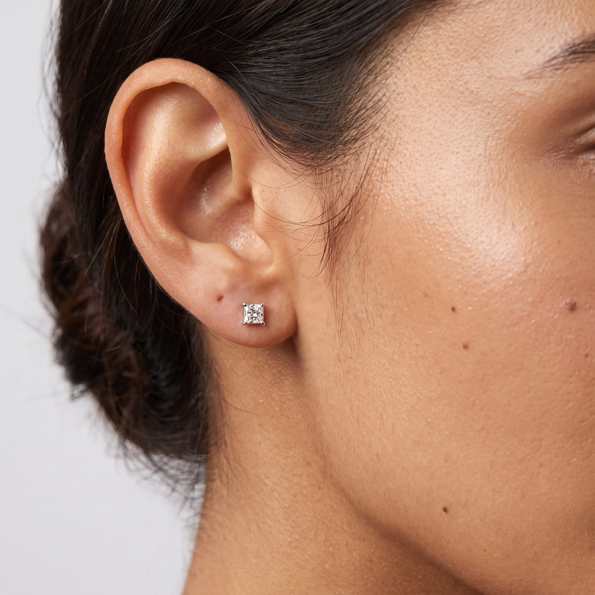 Close view of a woman wearing the Roxane Square Crystal Silver Studs flat to the lobe