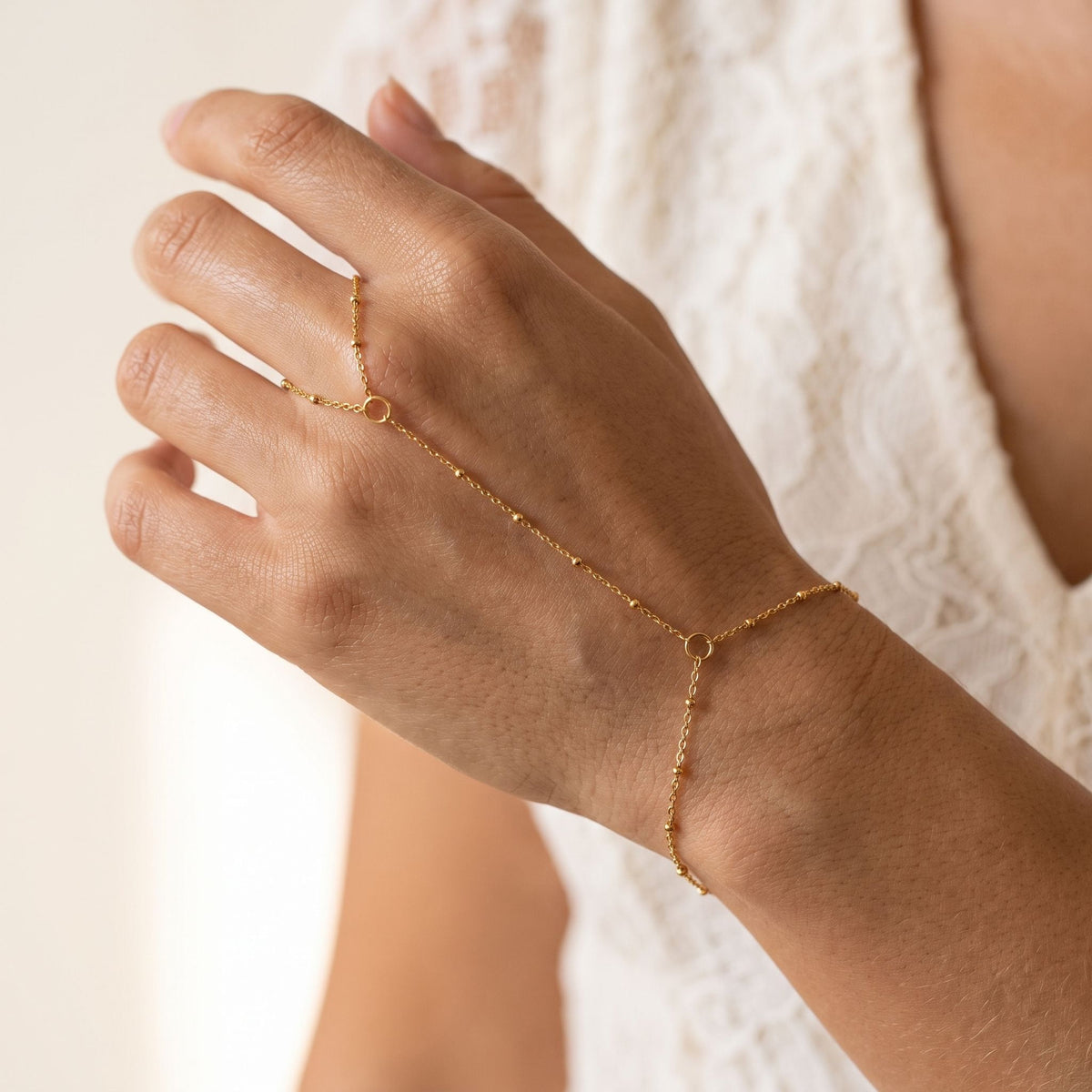 Satellite Hand Chain worn across the back of the hand, with the ring on the finger and the chain at the wrist.