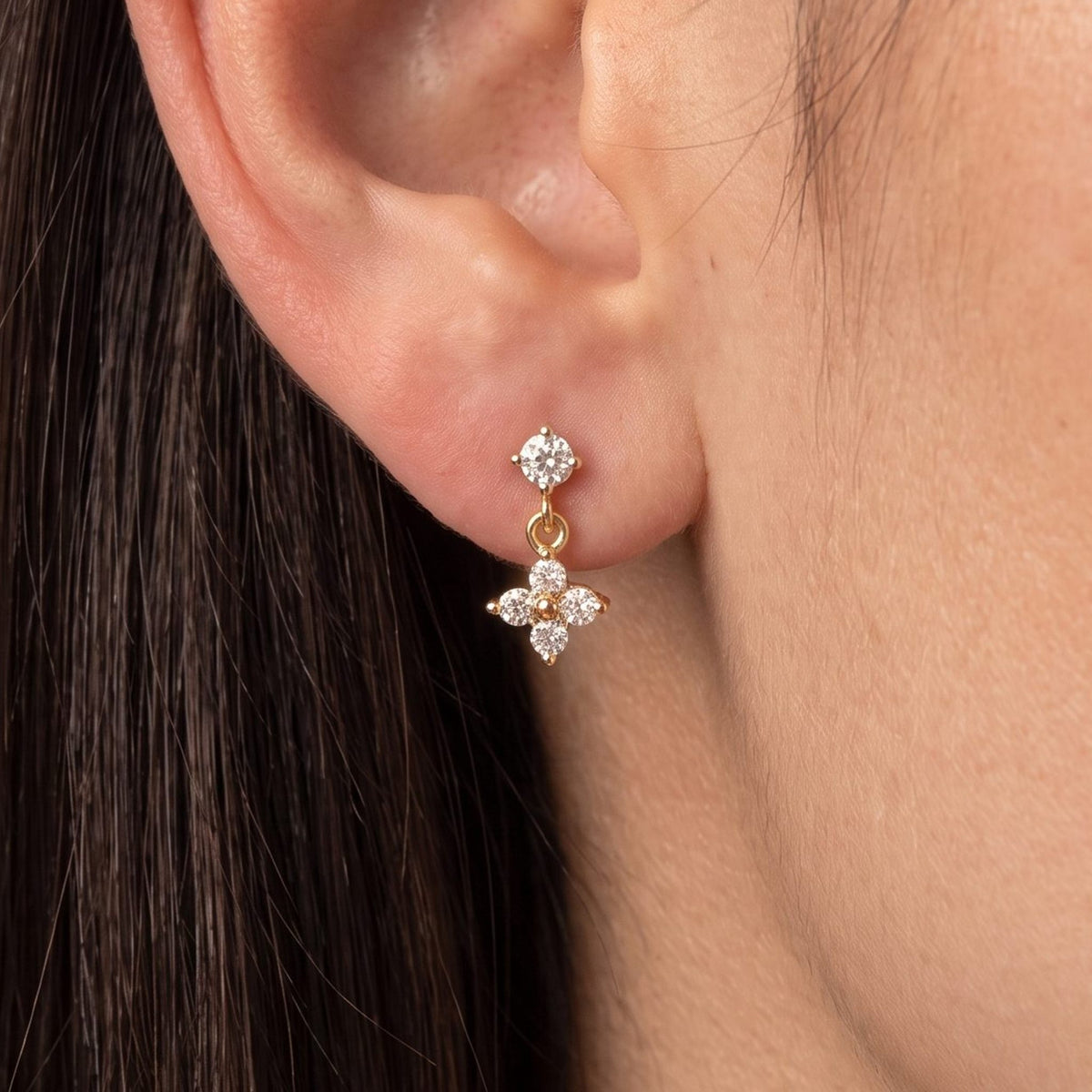 Close view of a woman wearing the Sienna Clover Crystal Drop Gold Earrings hanging below the lobe