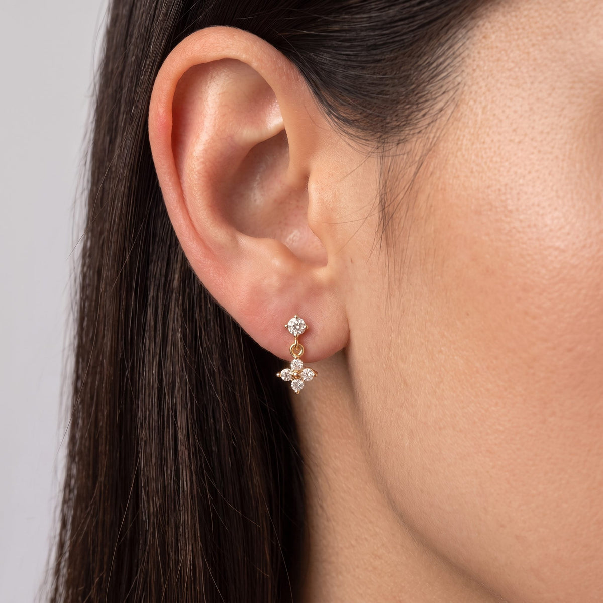 Close view of a woman wearing the Sienna Clover Crystal Drop Gold Earrings hanging below the lobe
