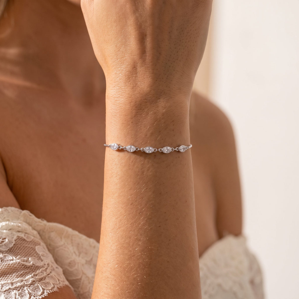 Woman wearing the Silver Oval Bezel Bracelet on the wrist, paired with a white lace top