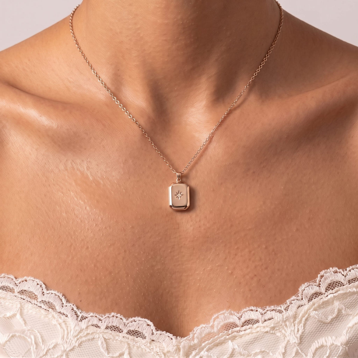 Close-up of the Star Pendant in rose gold, a star-set tag on a fine chain above a lace top
