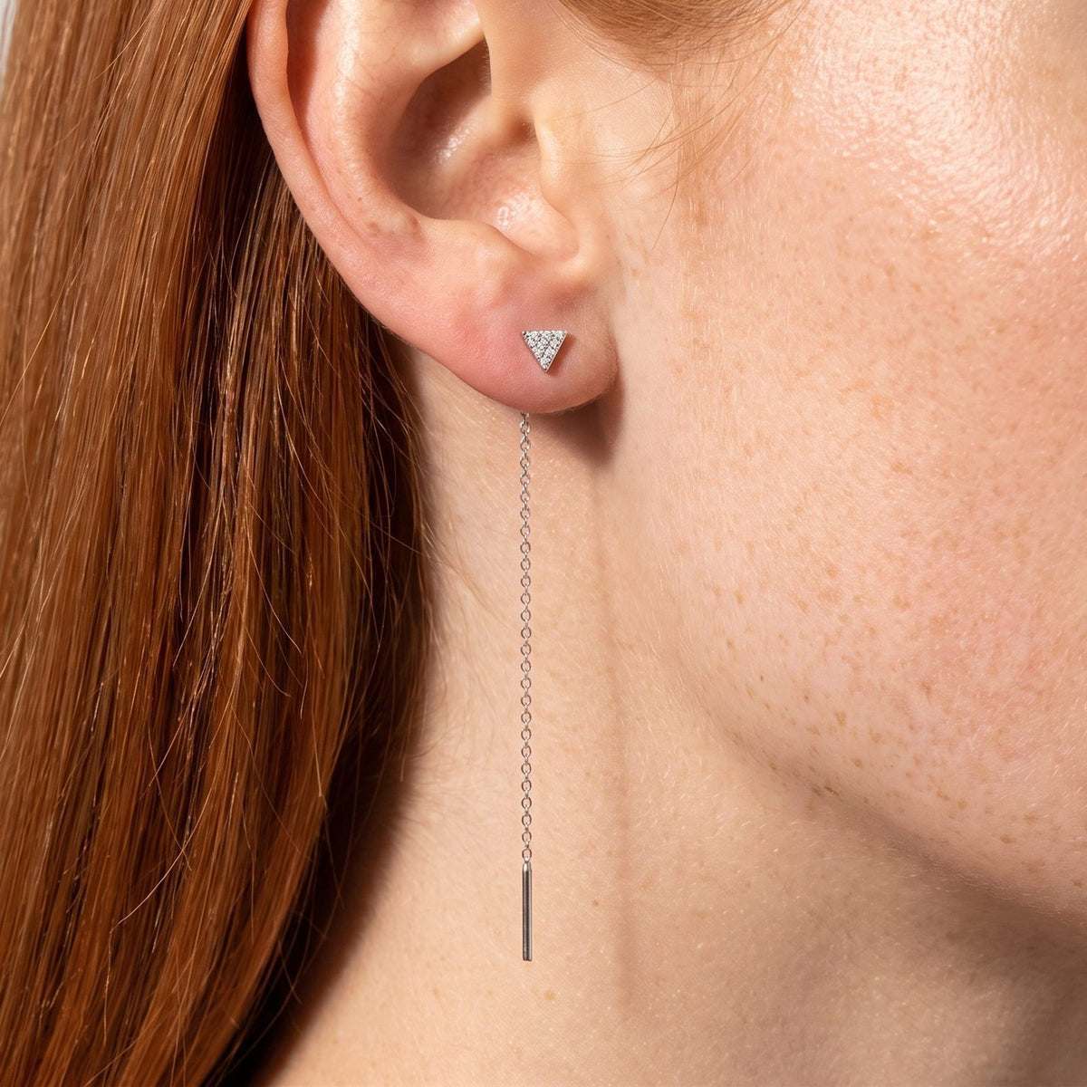 Woman wearing the Sofia Noir Drop Earrings through the lobe with a long silver chain hanging below