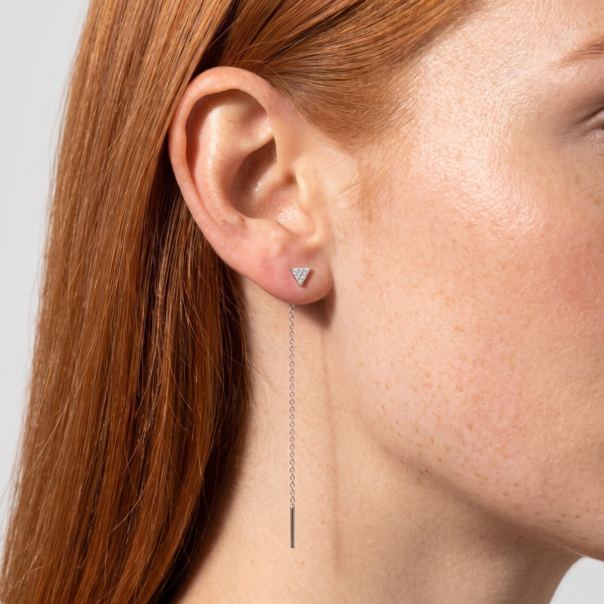 Woman wearing the Sofia Noir Drop Earrings through the lobe with a long silver chain hanging below