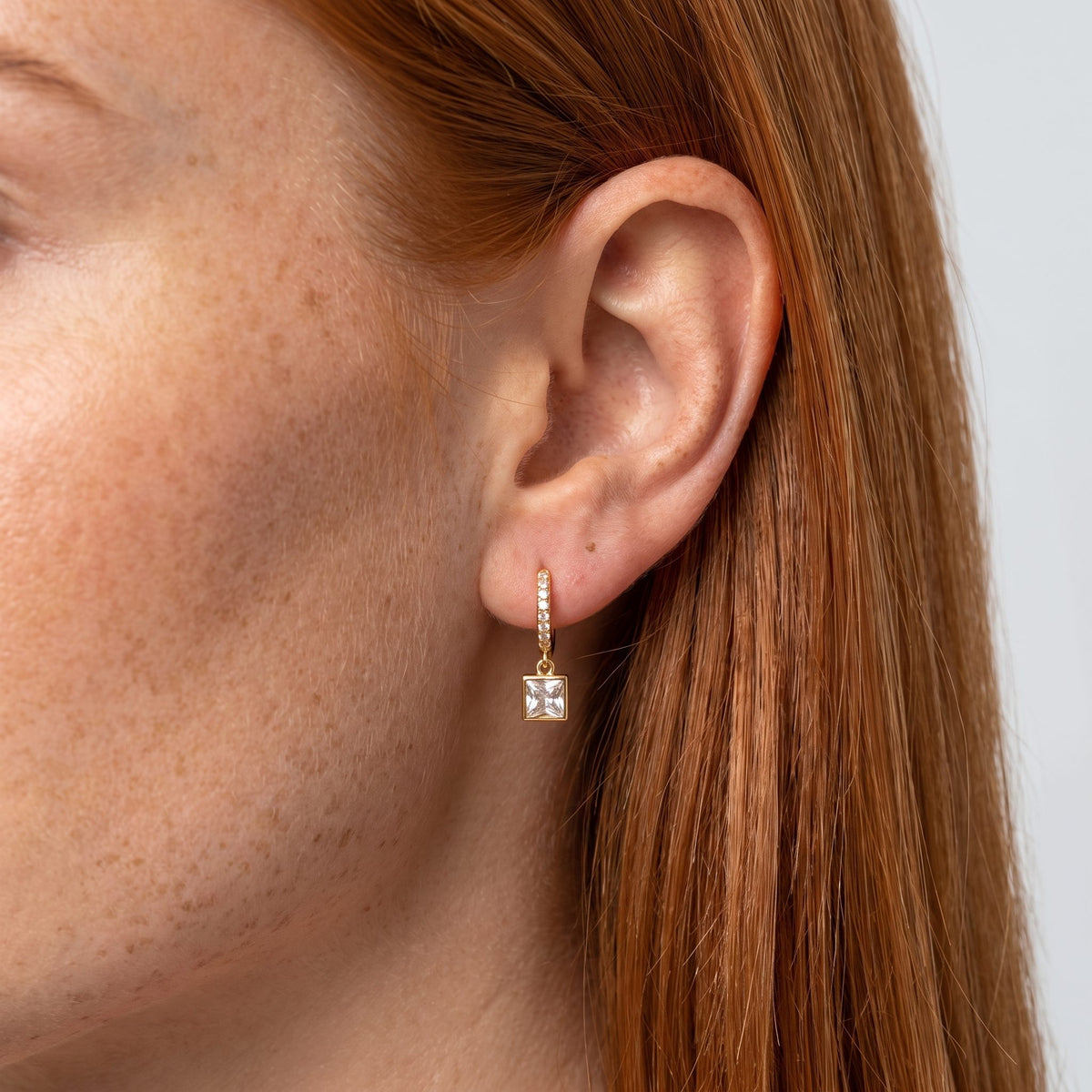 Woman wearing the Square Crystal Huggies on the ear, framed by her straight red hair