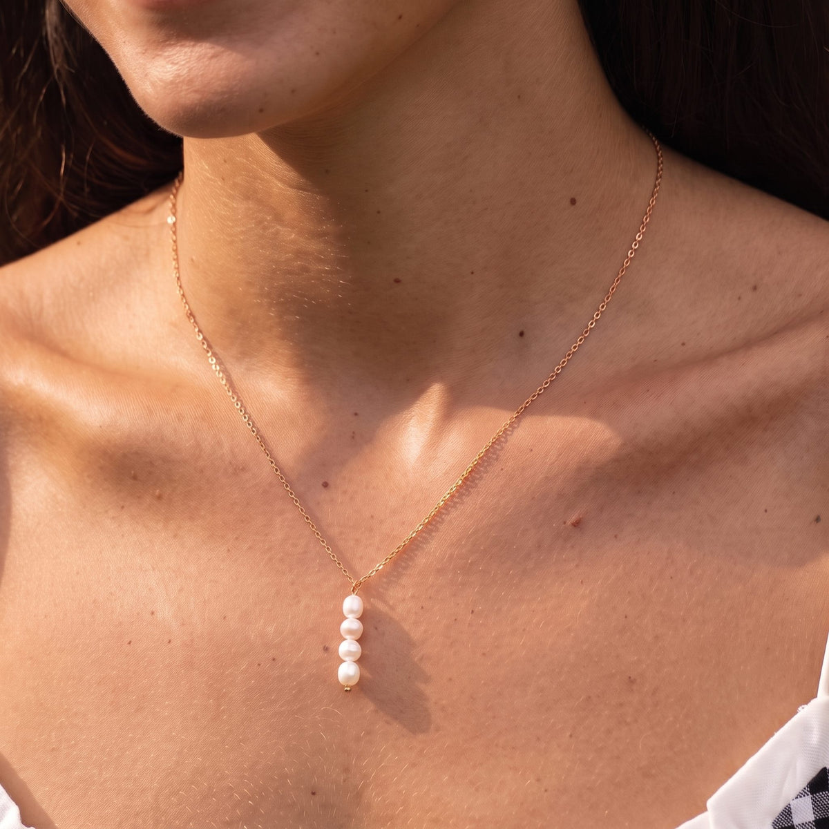 Close-up of the Stacked Pearl Pendant at the collarbone showing four pearls on a delicate rose gold chain