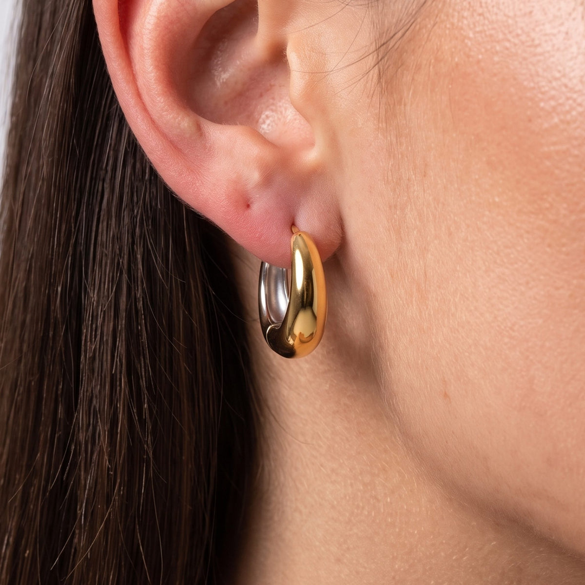Close-up of the Two-Tone Dome Hoops on the ear catching soft light