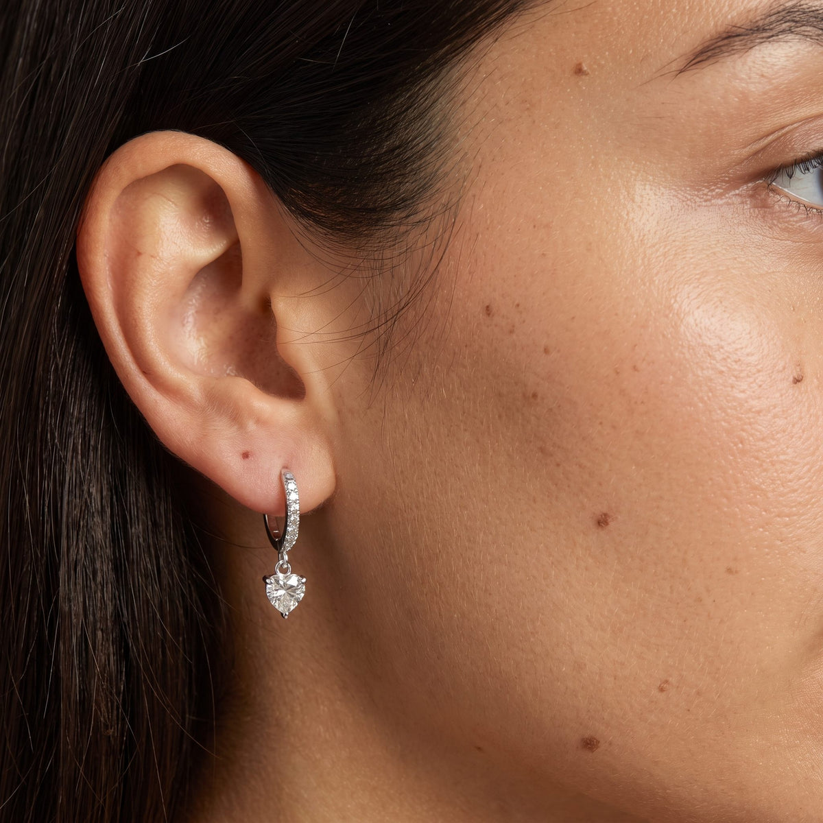 Woman wearing the Vittoria Crystal Heart Silver Earrings hanging below the lobe with a dangling heart-shaped crystal